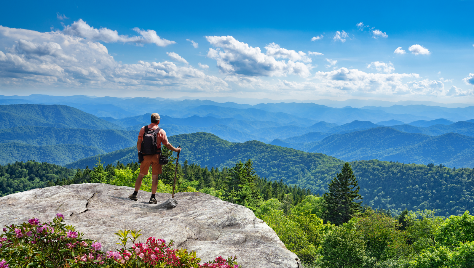 hiker standing on cliff looking out at Smoky Mountains view